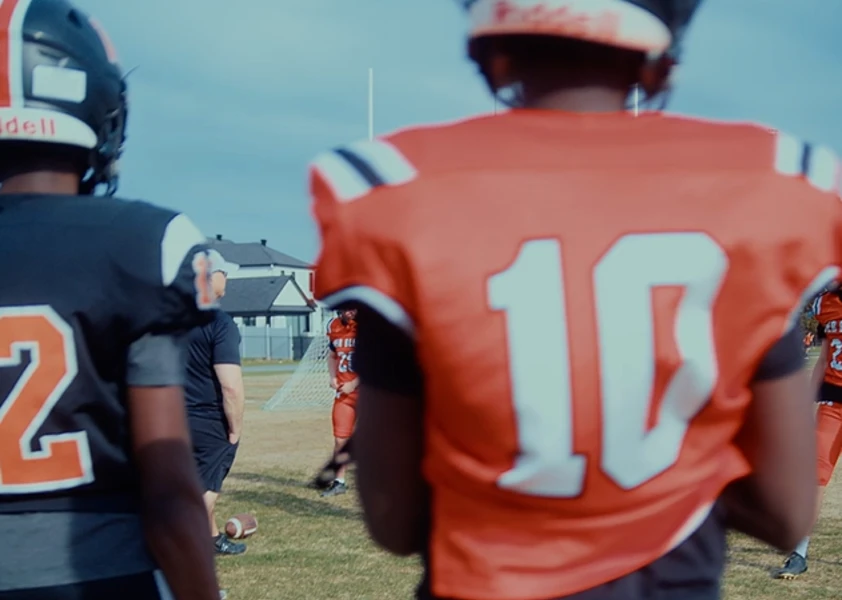 Des élèves en tenue de football dans un stade, sur le gazon du Collège catholique Mer Bleue
