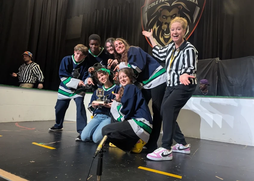 Équipe d’improvisation d’élèves posant avec leur trophée sur scène après une victoire lors d’un tournoi.