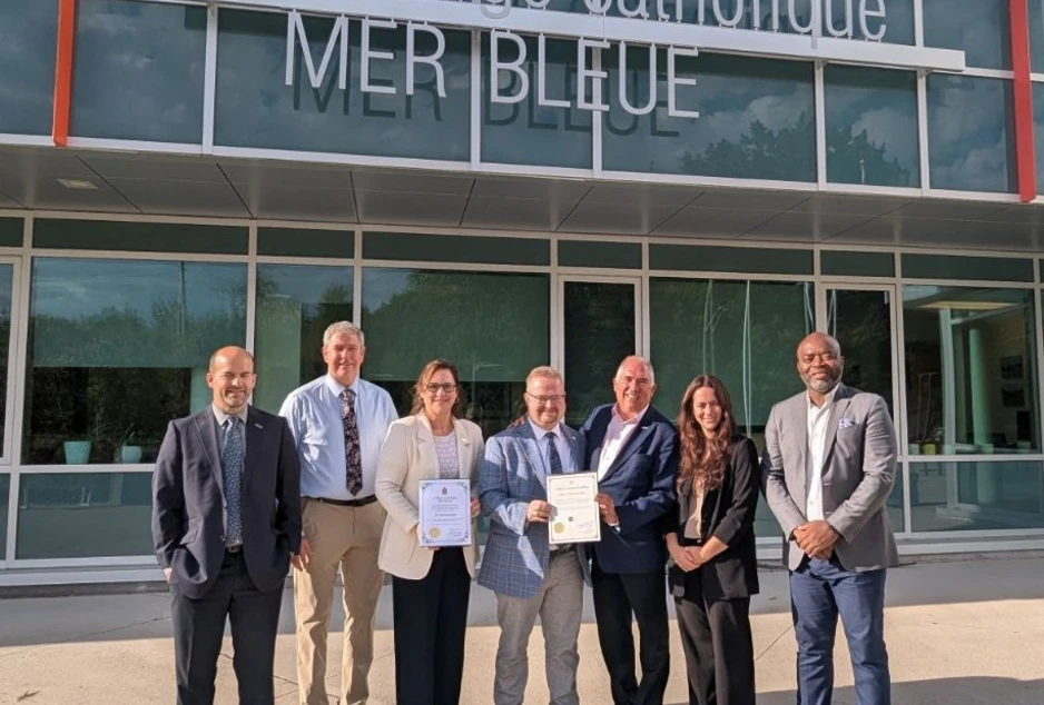 Des dignitaires et des membres de l’administration scolaire réunis devant le Collège catholique Mer Bleue pour célébrer le 10e anniversaire de l’école. Deux personnes tiennent des certificats commémoratifs.
