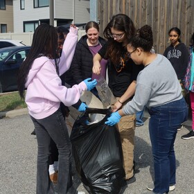 Groupe d'élèves qui ramassent des déchets dans un sac en plastique avec leur enseignante